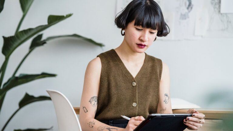 woman with tattoos drawing on tablet