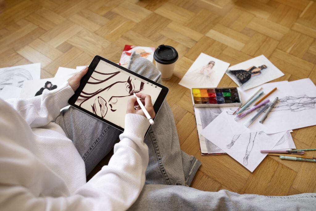 woman surrounded by art supplies and drawing a face on her tablet