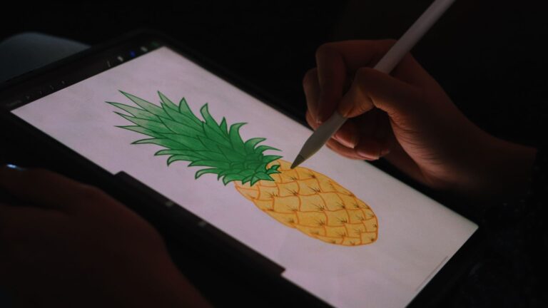 Digital illustration of a pineapple being drawn on a tablet using a stylus in low light, showcasing digital art on an iPad while using Procreate tools